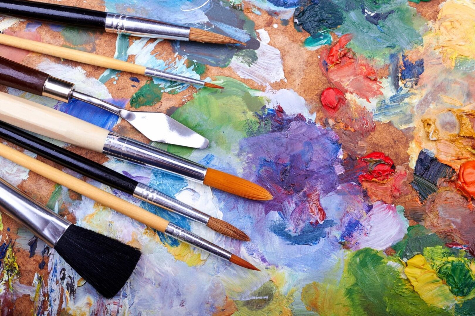 Paintbrushes and palette with colorful paint.